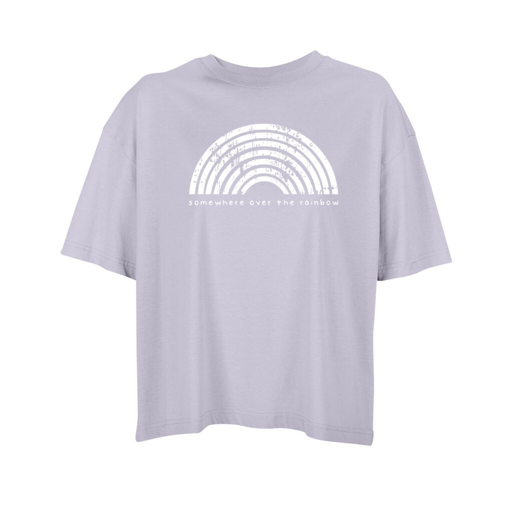 Ein Oversize-Shirt in leichtem Flieder, darauf der Regenbogen von Katja Dröll. Ein stilisierter Regenbogen aus sieben halbrunden Strichen, die zum Teil fleckig unterbrochen sind. Darunter der Schriftzug "somewhere over the rainbow"