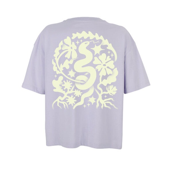 Ein Oversize-Shirt in leichtem Flieder, darauf das Snake-Motiv von Laura in hellgelb. Eine Schlange windet sich von unten nach oben, um sie herum verschiedene Blumen, Sterne, Äste, alles von Hand illustriert