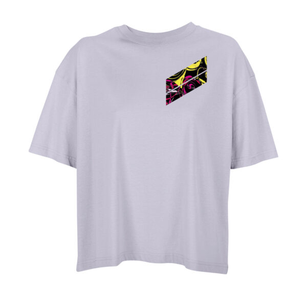 Vorderseite eines Oversize-Shirts in Flieder. Darauf zwei – durch einen schmalen weißen Strich getrennte – Diagonalen, relativ kurz, jeweils vertikal endend, sitzen sie auf der linken Brust, von rechts oben nach links unten laufend. In den Diagonalen abstrakt miteinander vermischte Farben, hauptsächlich Schwarz, Gelb, Rot und Pink, wie mit verschiedenen Pinseln verrührt, aber ohne verlaufende Übergänge.